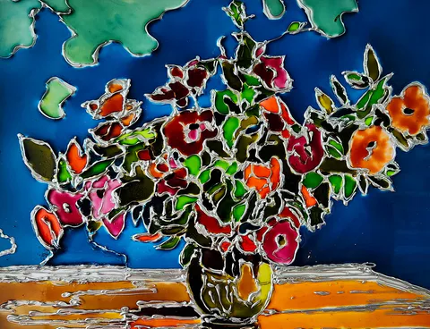 Red, magenta, and orange blossoms crowd a dark vase on an amber table, their silver-coloured outlines glowing against cobalt blue