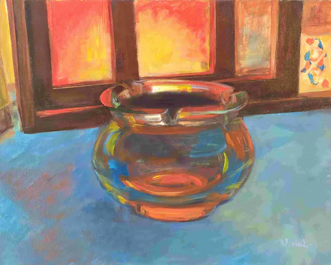 A round crystal vessel catches warm window light, scattering amber reflections across a blue tabletop
